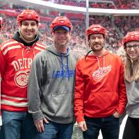 Six alumni smile for a photo together while getting prepared to get on the ice at the Detroit Red Wings GVSU Night
